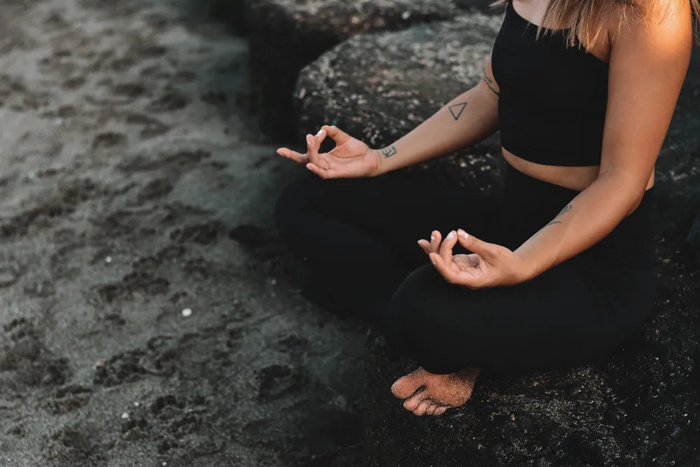 Frau am Strand, die Yoga praktiziert